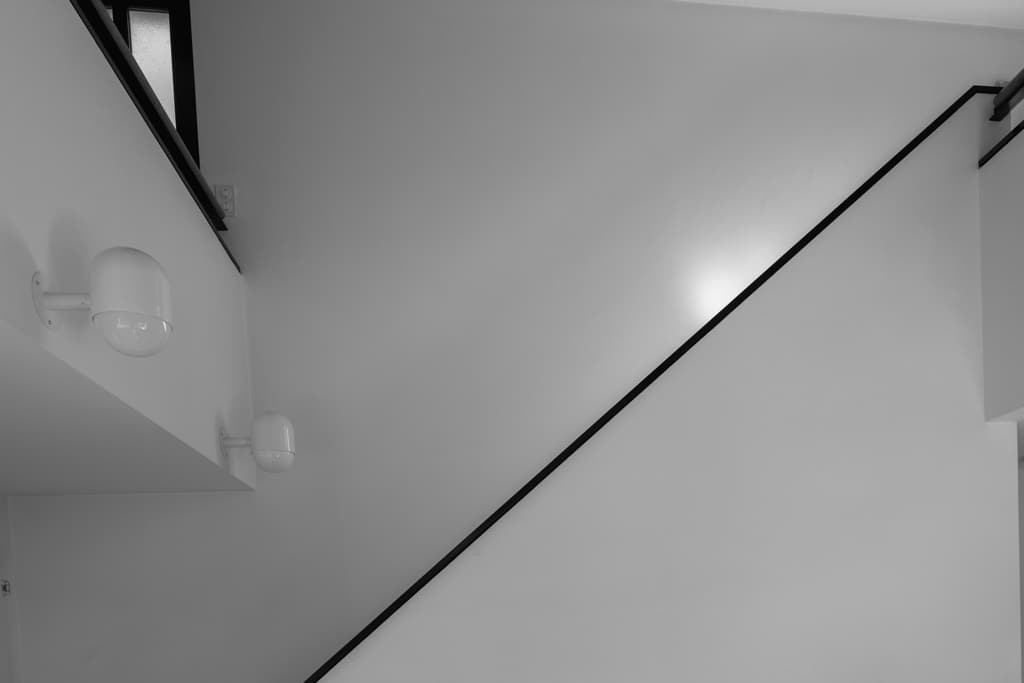 Schwarz-weisse Treppe der Casa Walser mit klaren Linien, weissen Wänden und schwarzem Geländer