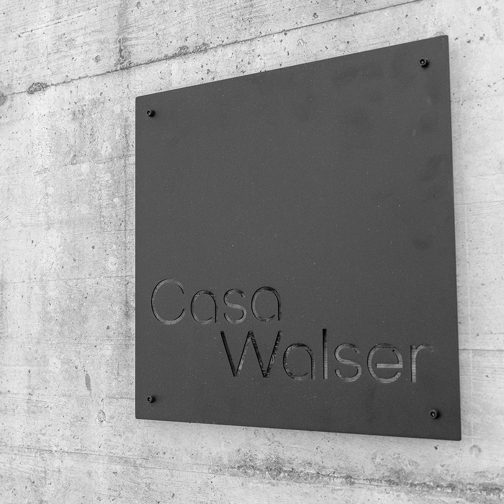 Beschriftung Casa Walser auf einer Wandtafel vor Sichtbeton