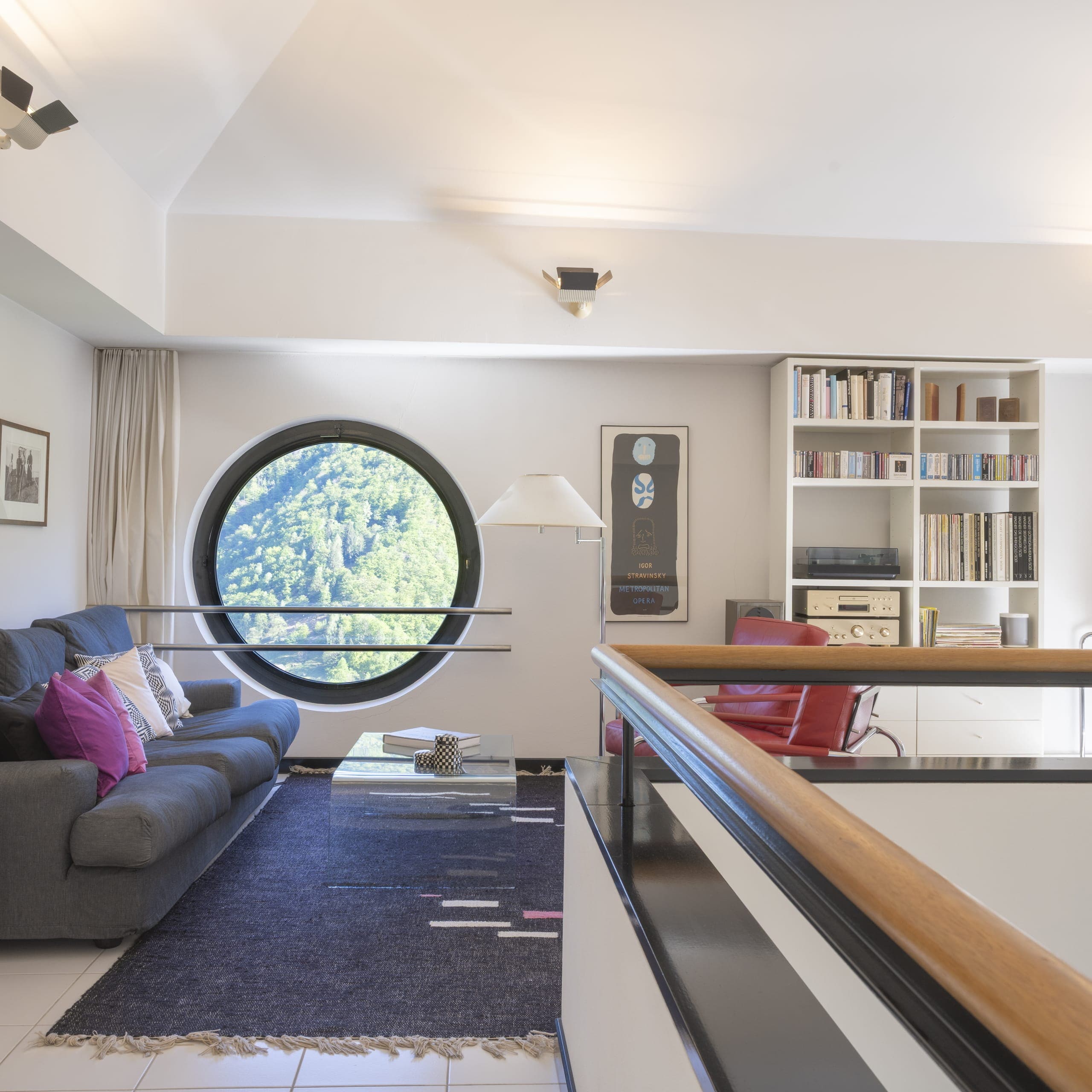 Innenraum der Casa Walser mit rundem Fenster, Sichtbeton und minimalistischem Wohnbereich