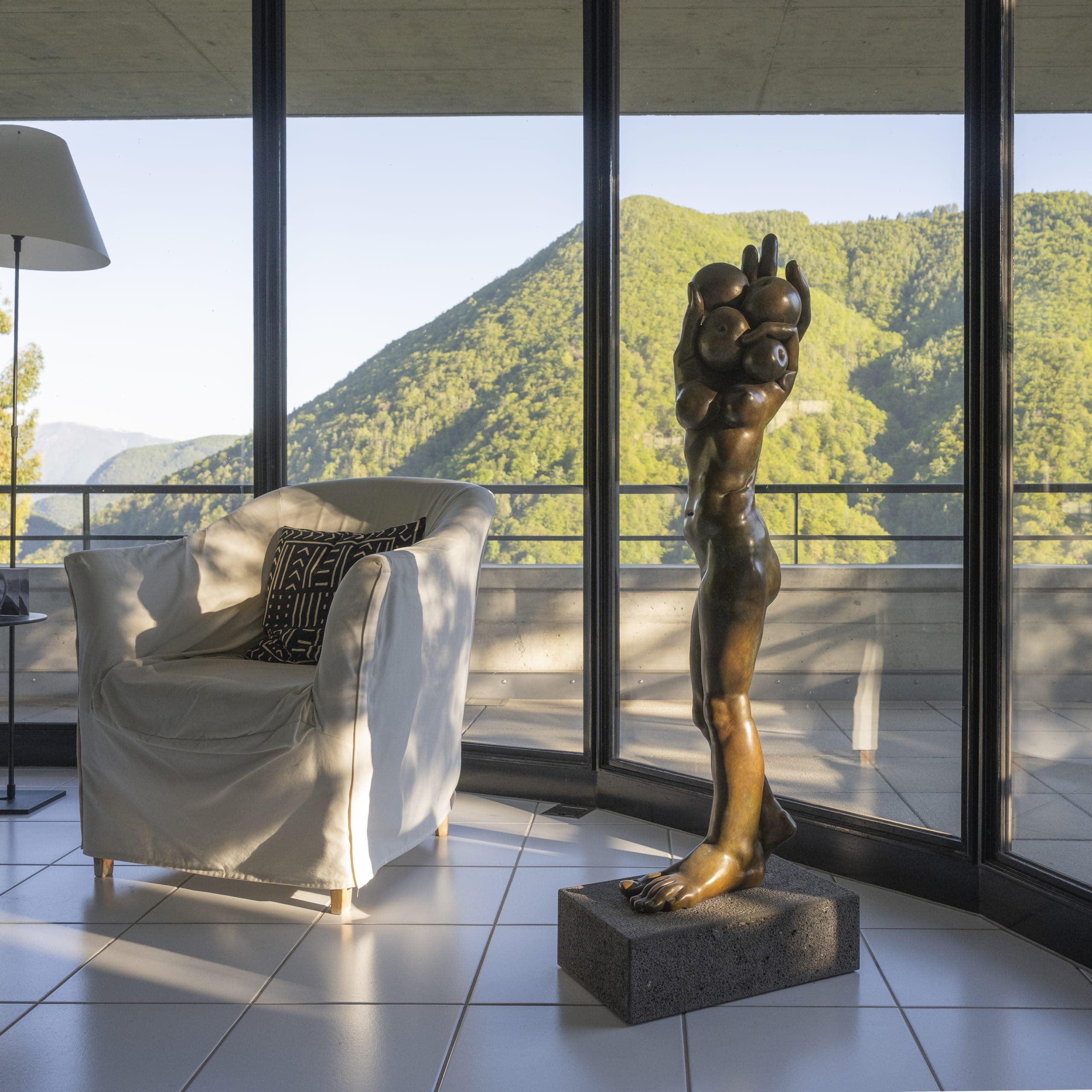 Innenraum der Casa Walser mit Skulptur, Glasfront und Blick auf die Tessiner Berglandschaft